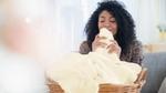 A person pulling a blanket from a basket close to their nose and smelling it.