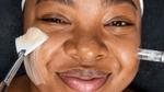 Young woman with melanin-rich skin undergoing a beauty treatment from a Dermalogica skincare professional