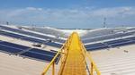 A yellow metal walkway runs through the centre of an array of solar panels on the roof of a Unilever building in India.