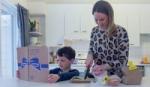 Mother and child in kitchen preparing a meal from a Hellmann’s recipe book.
