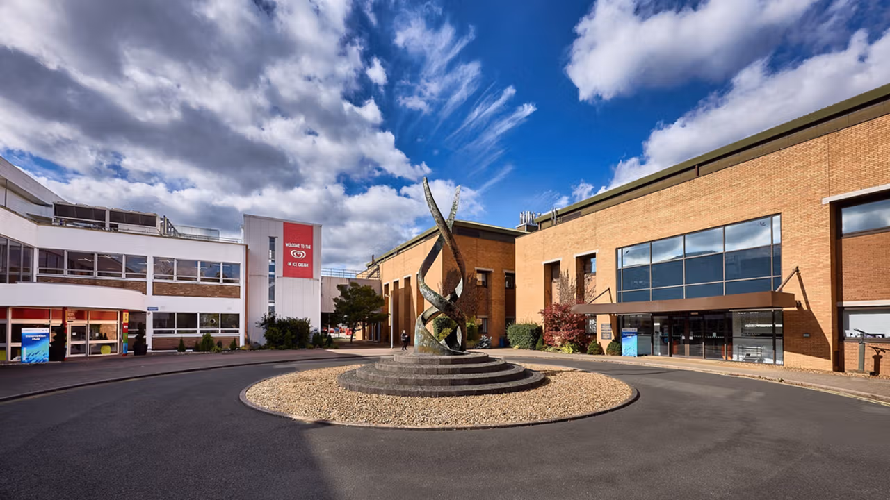 Several low-level office buildings, some white and some red brick, with a circular drive and an ornamental structure in the foreground.