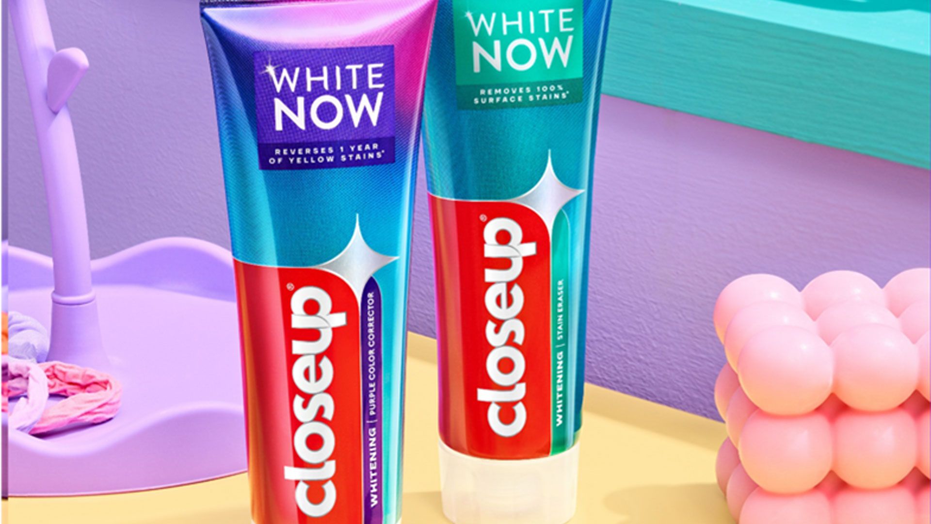 Two tubes of Closeup toothpaste labeled "White Now", displayed on a colorful background.