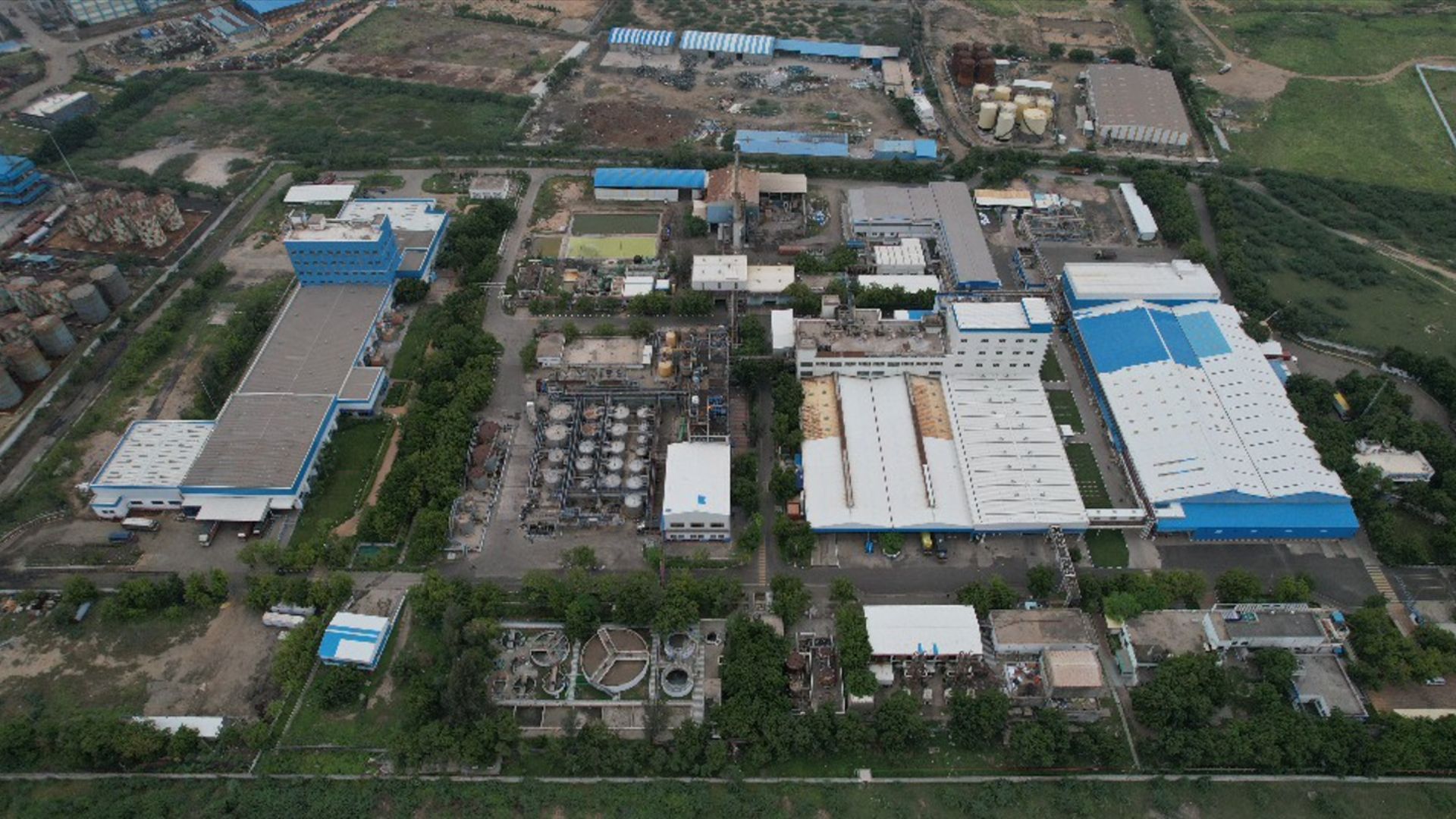 An aerial view of Unilever's Gandhidham factory in India,. Blue, grey and white rooftops surrounded by green fields.