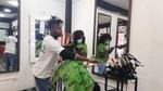 Man in hair salon styling and adding treatments to a woman’s hair