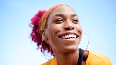 Young woman smiling against a blue sky