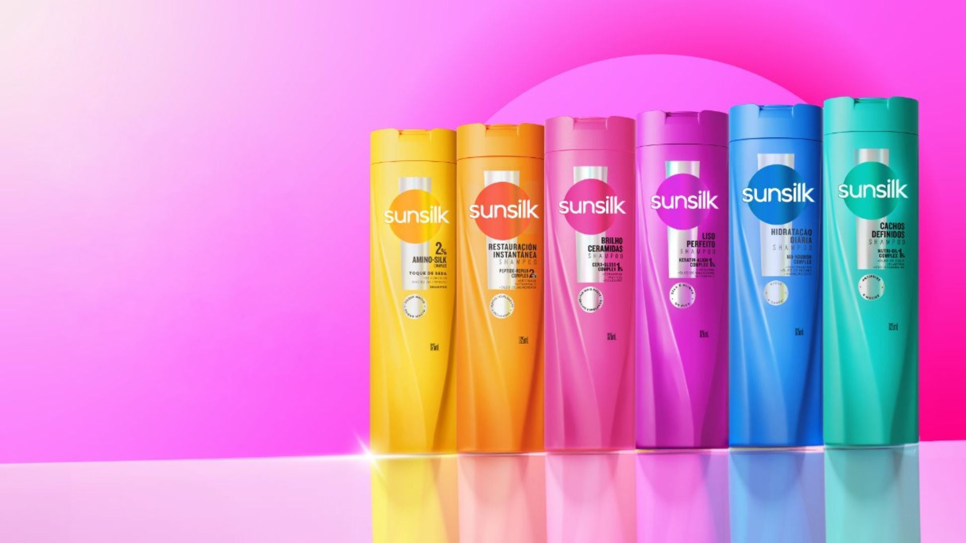 Six colourful bottles of new Sunsilk shampoo on a pink background. Sunsilk is part of Unilever Beauty & Wellbeing. 