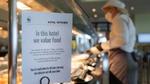 A chef working in a kitchen with a clear sign declaring that the kitchen works to ensure food is not wasted