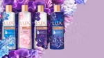 Four bottles of LUX bodywash on a bed of flowers. The bed of flowers is resting on a lavender background.