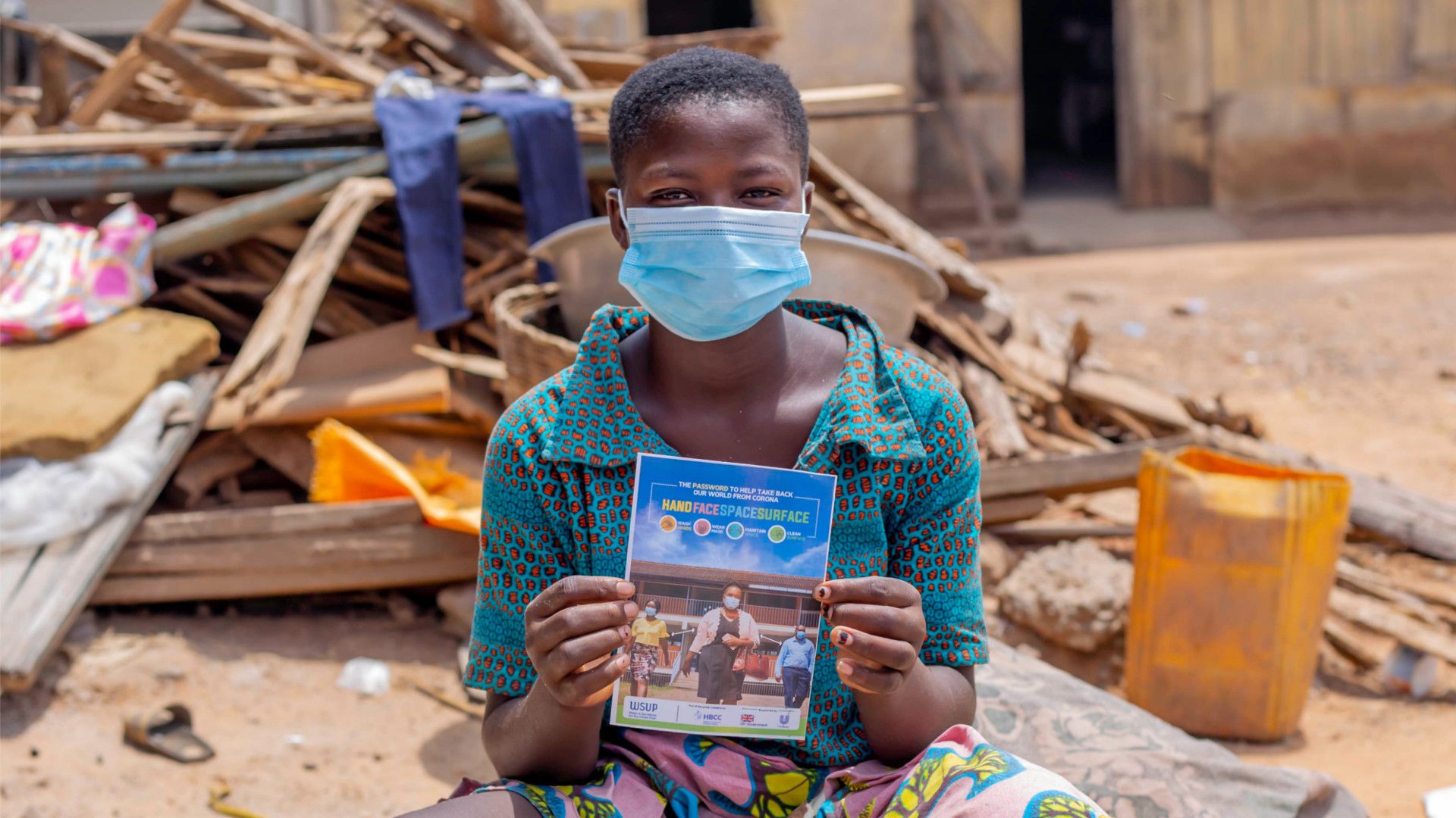 Youth holding a poster of the ‘Hands–Face–Space–Surface’ password from the global hygiene campaign created for the coalition