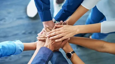 Group of hands stacked together symbolizing teamwork