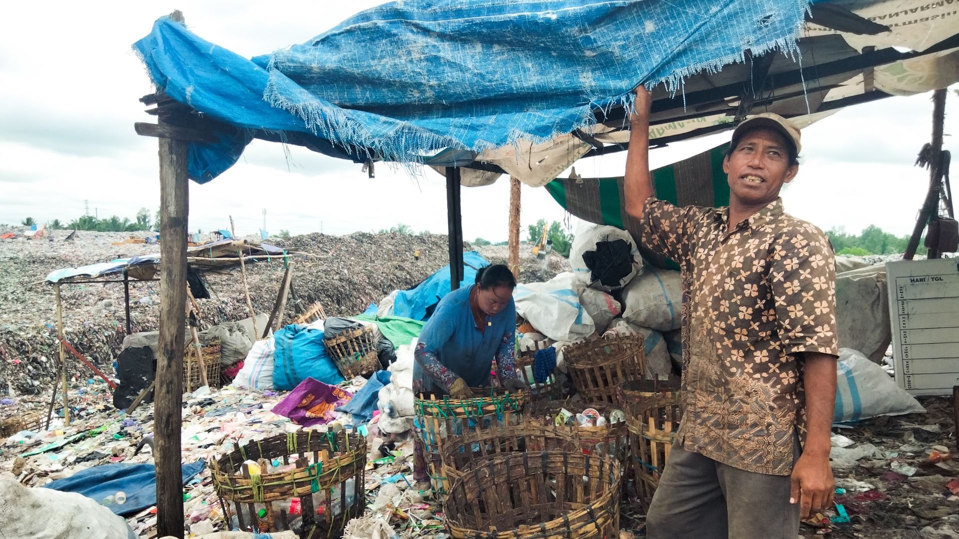 Two waste workers sorting through plastic 