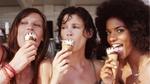 Three women smiling into the camera eating Cornetto ice creams on a sunny day