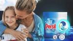 Adult hugging child beside Persil Ultimate Non Bio pack, highlighting stain removal and fabric care benefits.