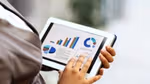 A close-up of a businesswoman wearing a suit using a tablet to view financial data