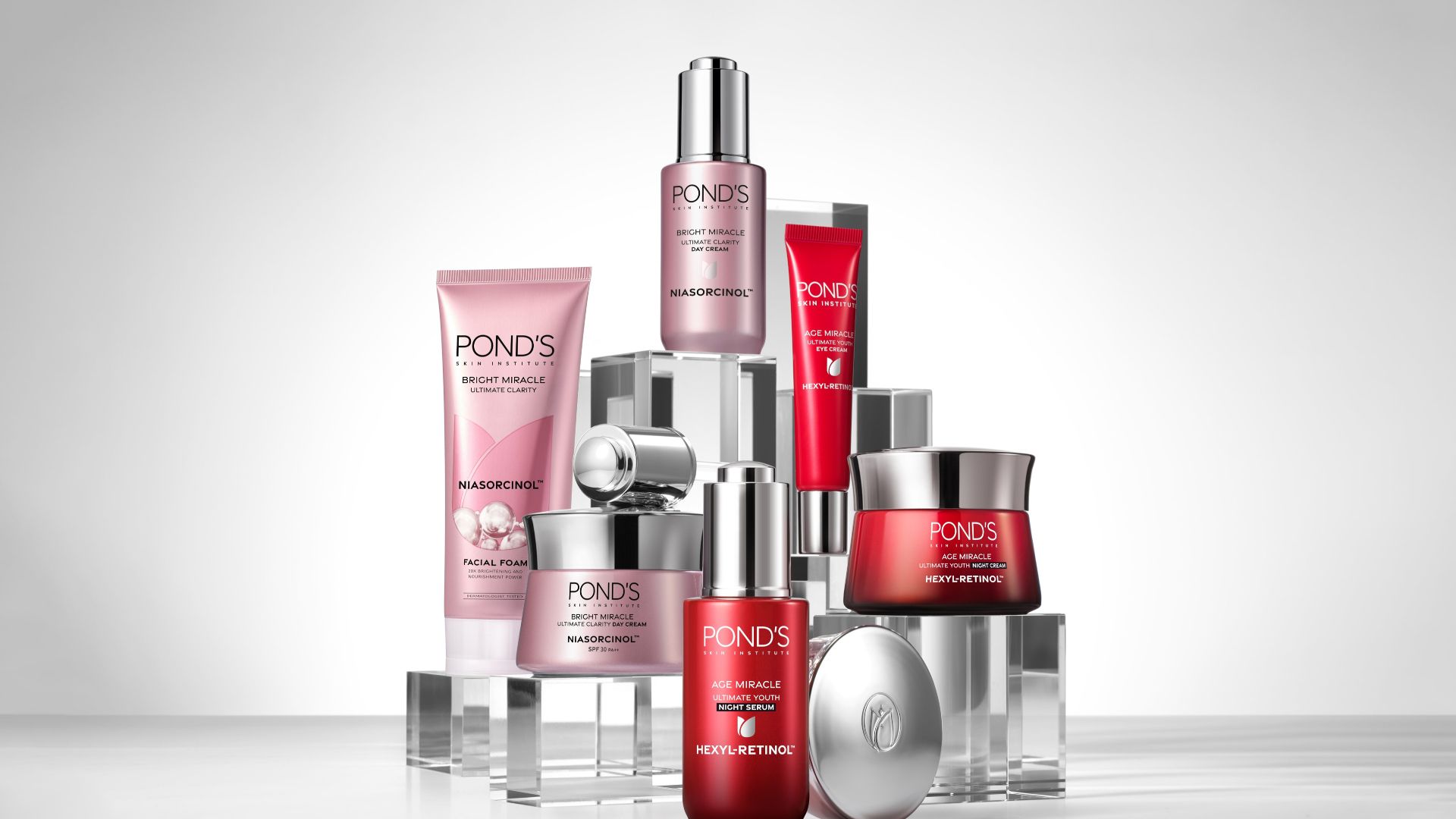 A selection of red and pink Pond’s skincare products in tubes and pots arranged in a pyramid shape.