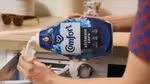 Person pouring Comfort fabric conditioner into bottle cap ready to put in washing machine.