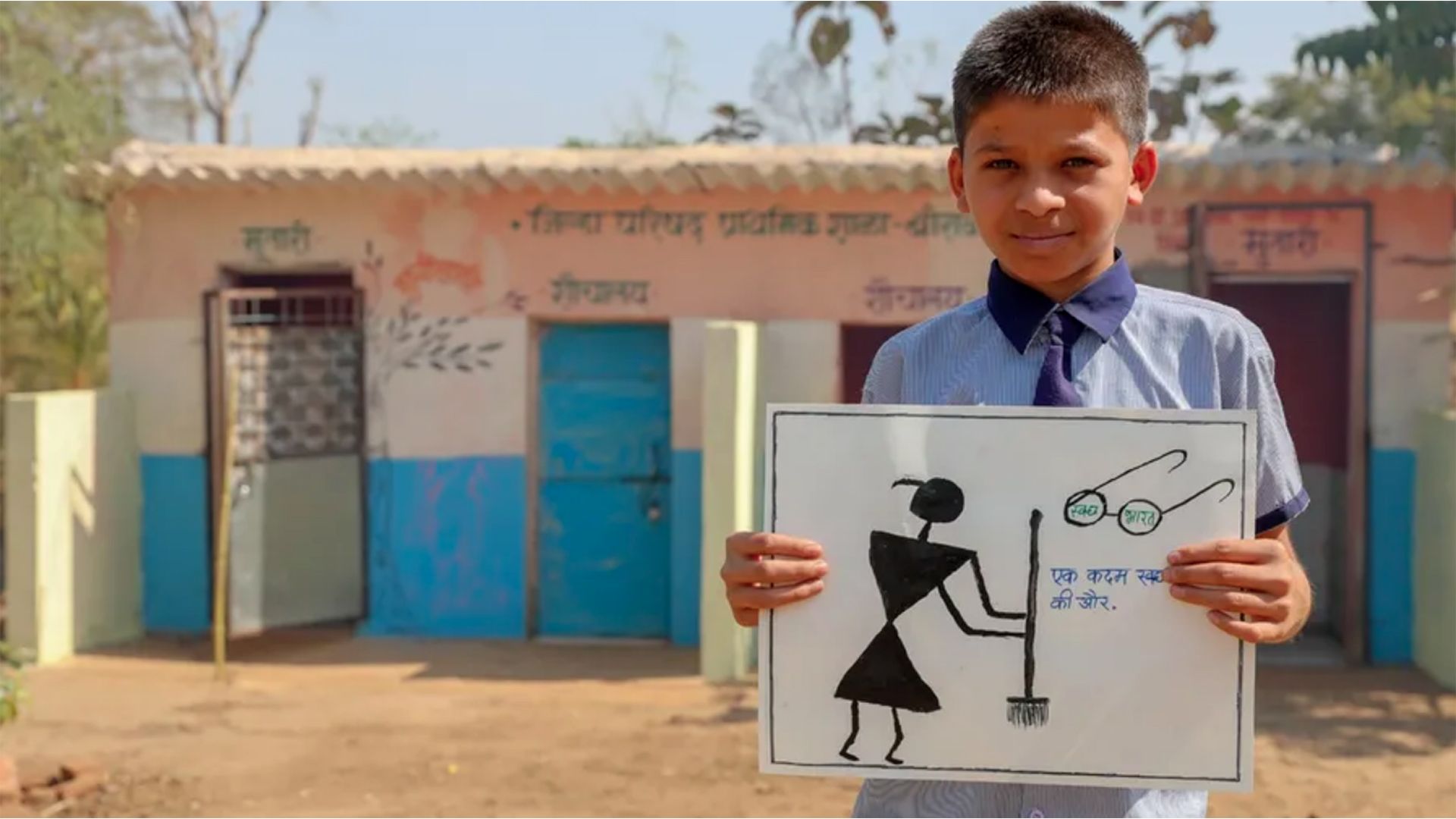Boy with a poster showing how to unblock a toilet standing near a public toilet block 
