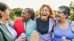 Four women laughing together outdoors.
