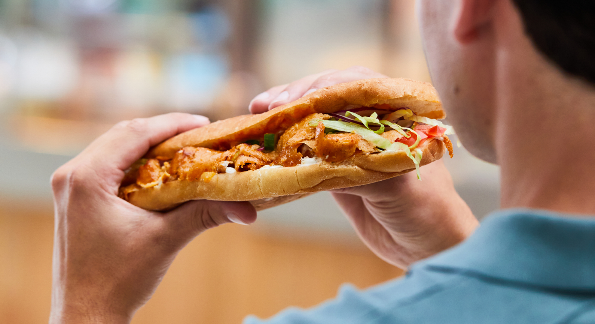 Back view of a man preparing to eat a large döner kebab 