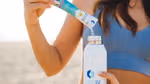 Woman pouring powdered Liquid I.V. electrolyte drink mix from a sachet into a bottle.