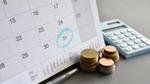 The view of a desk showing a calendar with the 31st circled. On the desk is a pen, a calculator and three piles of coins