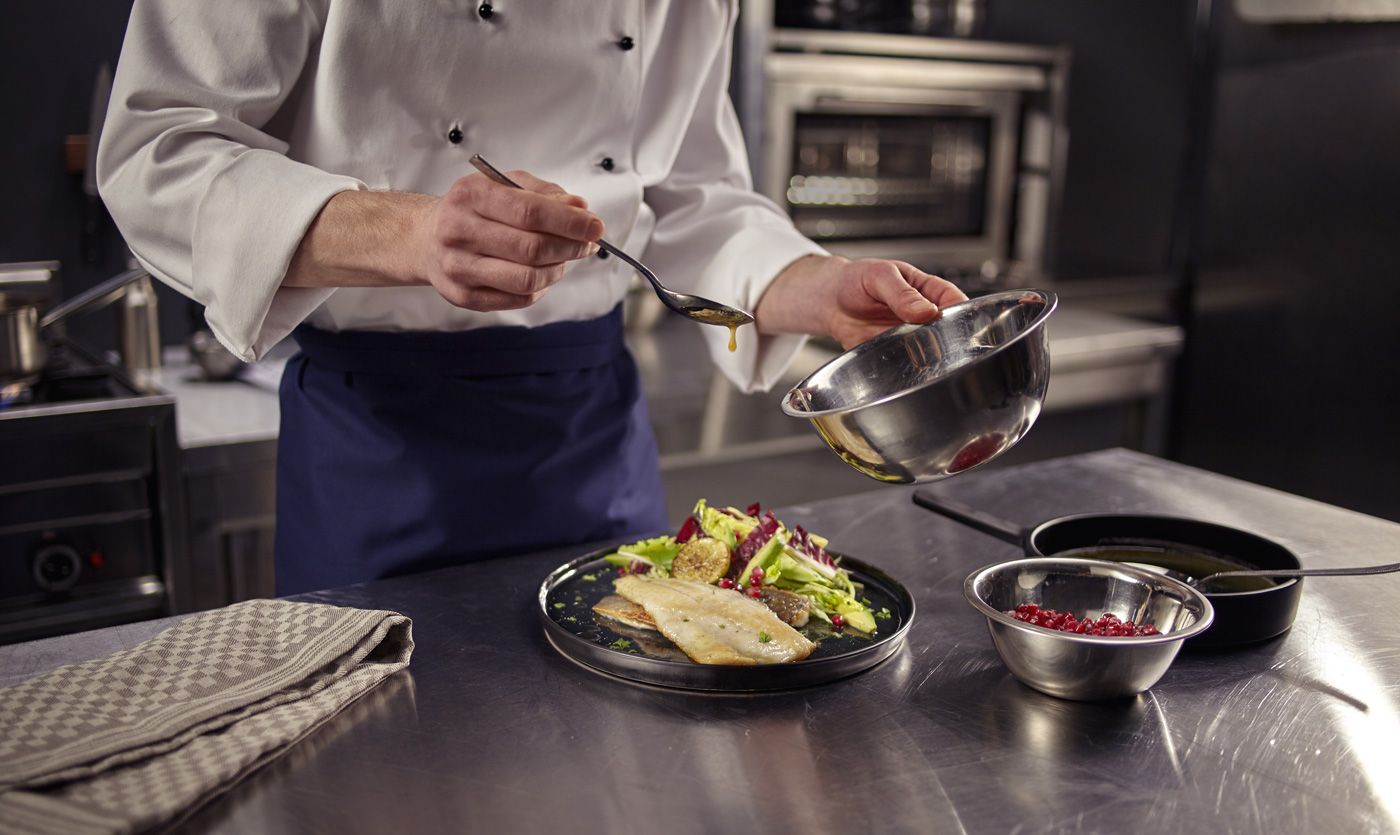 Chef in a commercial kitchen preparing a dish using a Knorr product.