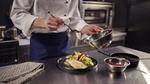 Chef in a commercial kitchen preparing a dish using a Knorr product.