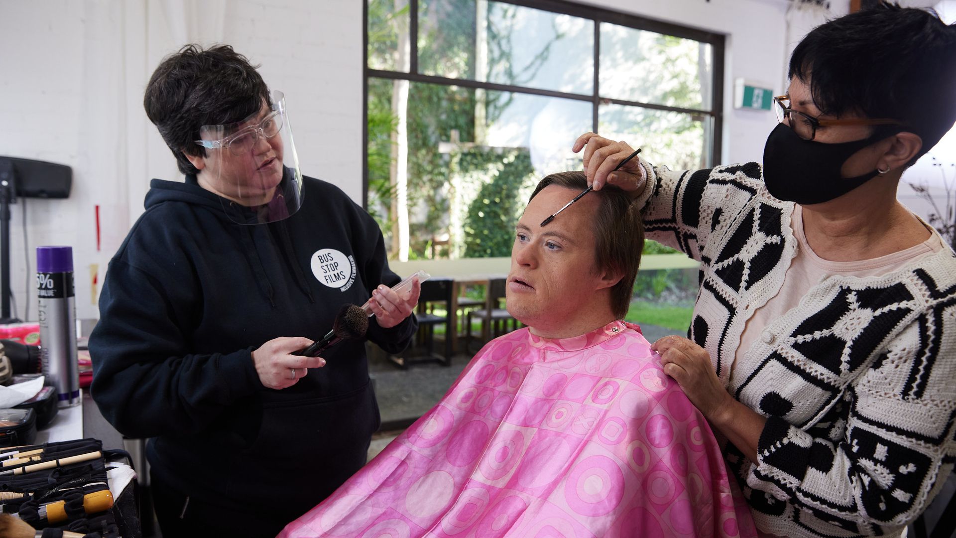 Make-up team preparing an actor with disabilities for his front of camera role on set 