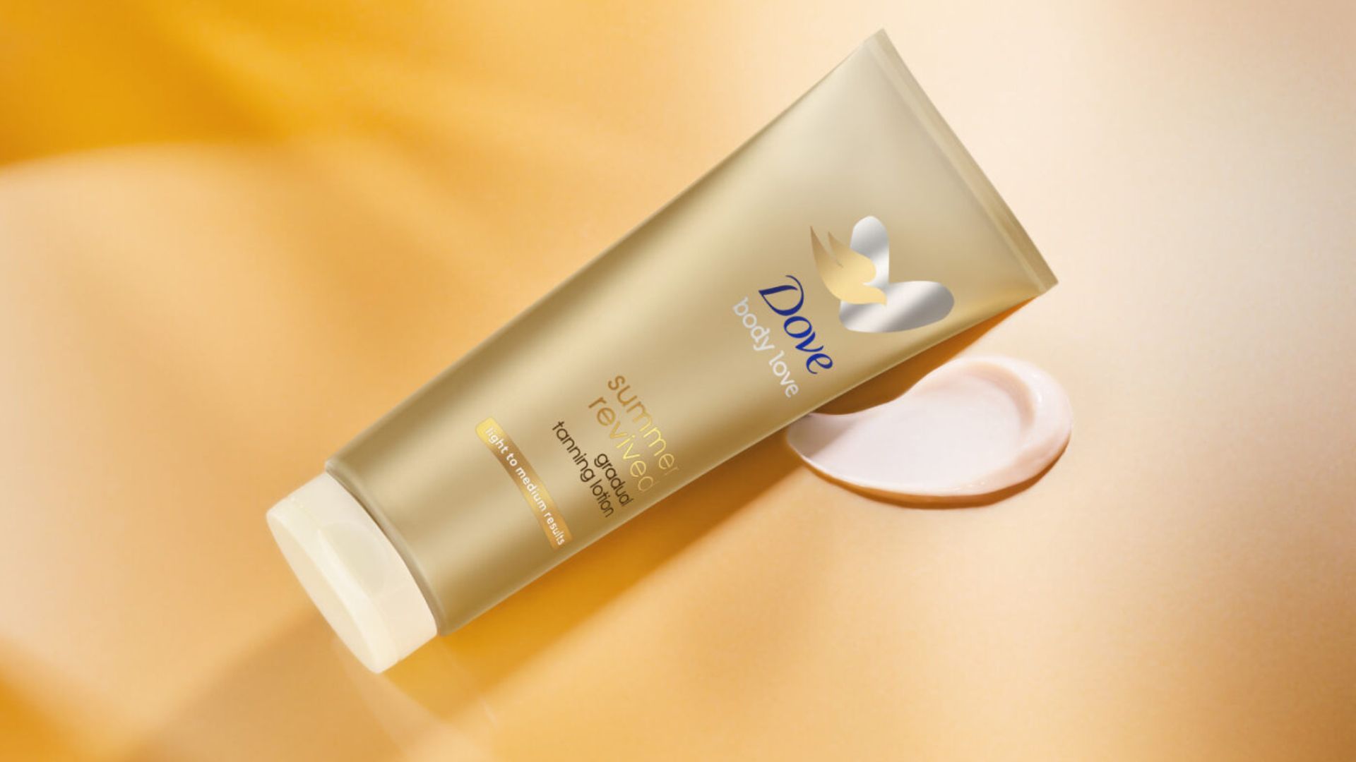 Dove Summer Revived lotion from Dove’s gradual tan range to give skin a summer glow. Product shown with amber background