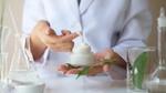 A person holding a jar of cream