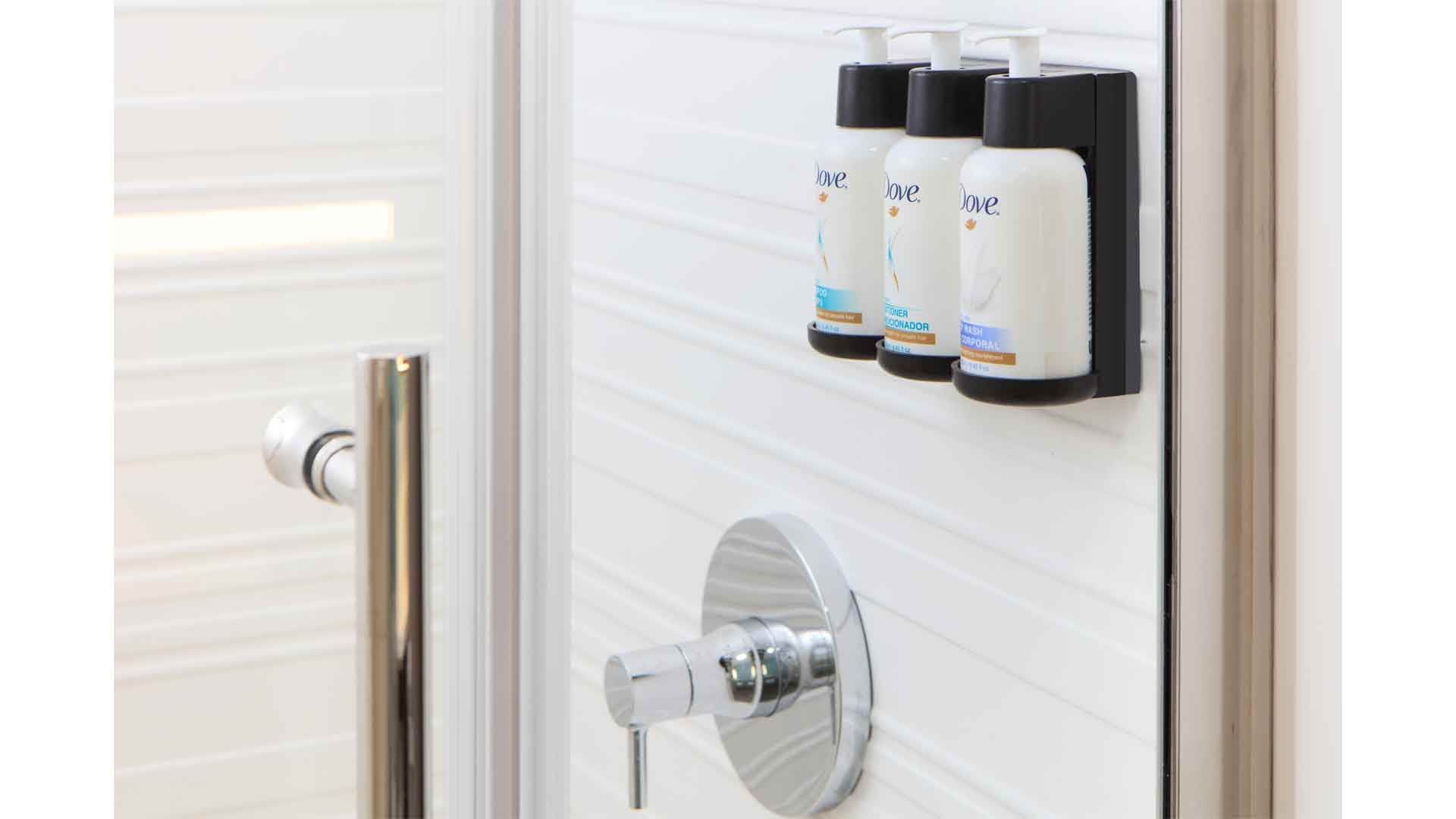 A Dove shower gel pump in a hotel shower