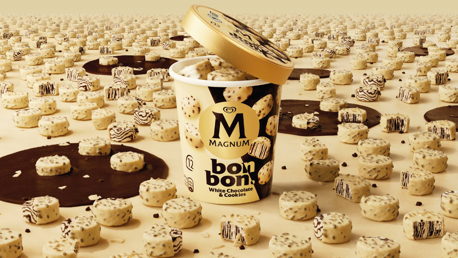 A tub of White Chocolate & Cookies Magnum Bon Bon with an open lid. The tub is surrounded by Bon Bon pieces.