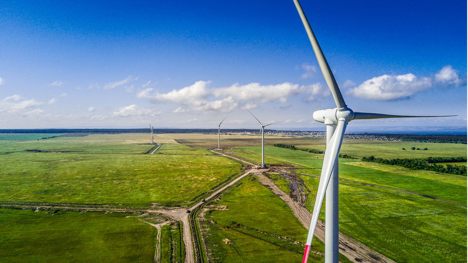 Image of wind turbines turning and generating electricity in a green field