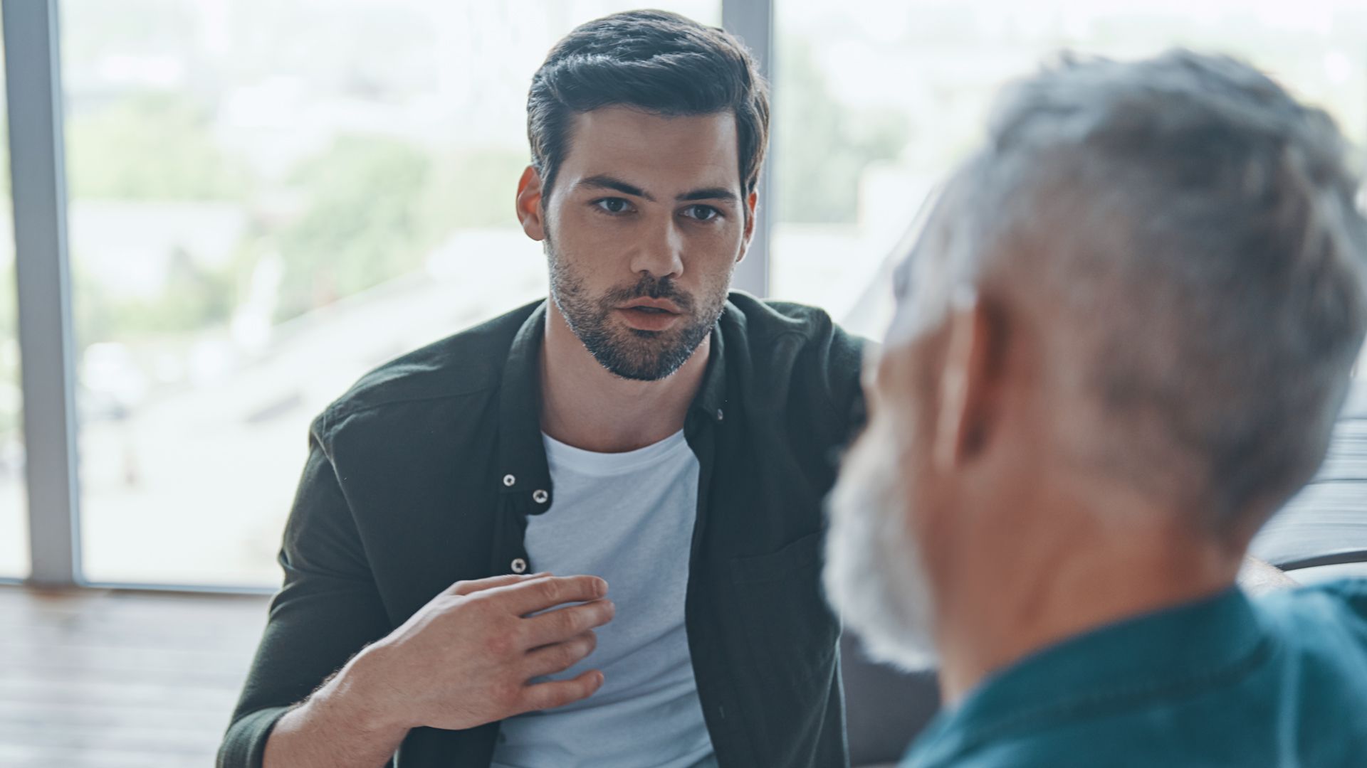 Two men sitting facing each other, engaged in a conversation.