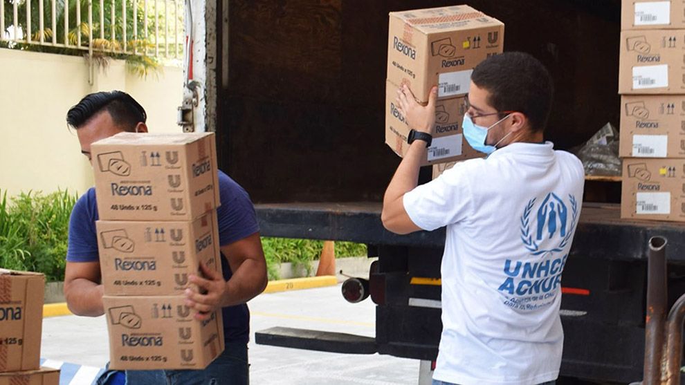 Photo of two men taking and carrying boxes from the back of a truck 