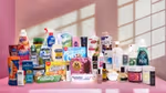 A collection of Unilever’s products arranged on a pink surface with a pink background. The products include laundry detergents, fabric softeners, dishwashing liquids, toothpaste, deodorants, shampoos, conditioners, body washes, skincare items, dressings, ice creams and vitamins.
