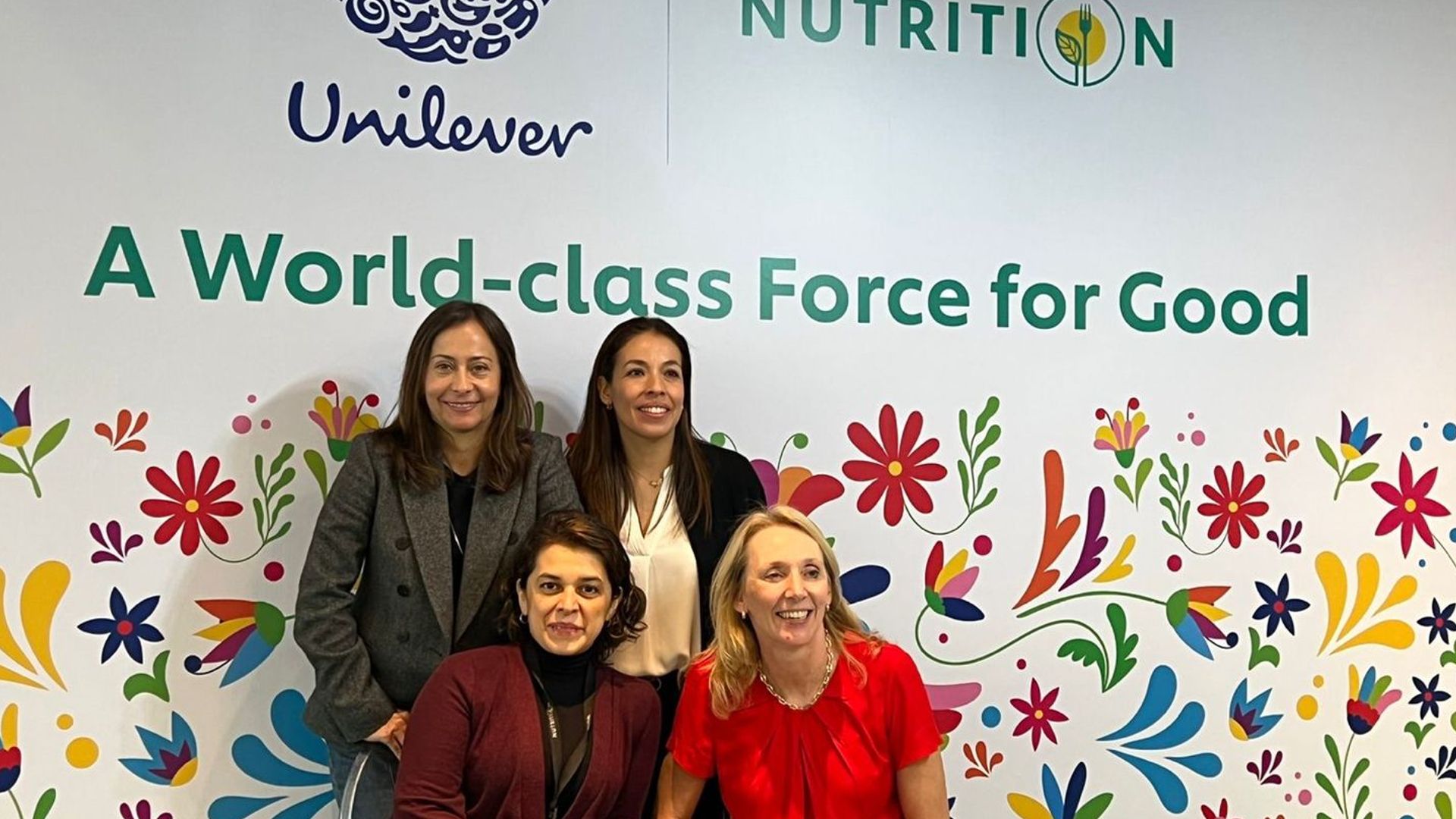 Hanneke Faber poses with three female colleagues in front of flower mural