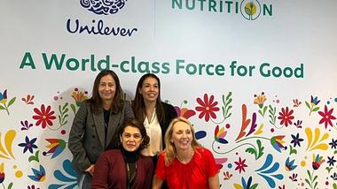Hanneke Faber poses with three female colleagues in front of flower mural