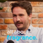 Man speaking in front of a brick wall with the text “all about fragrance.”