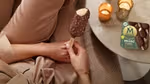 Woman sitting beside a table with a multi-pack of vegan Mini Magnums and holding a vegan Mini Magnum in her hand