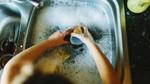 Hands in a sink washing up dirty dishes