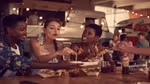 Three people sat at a table in front of takeaway food cartons, drinking Lipton Ice Tea.
