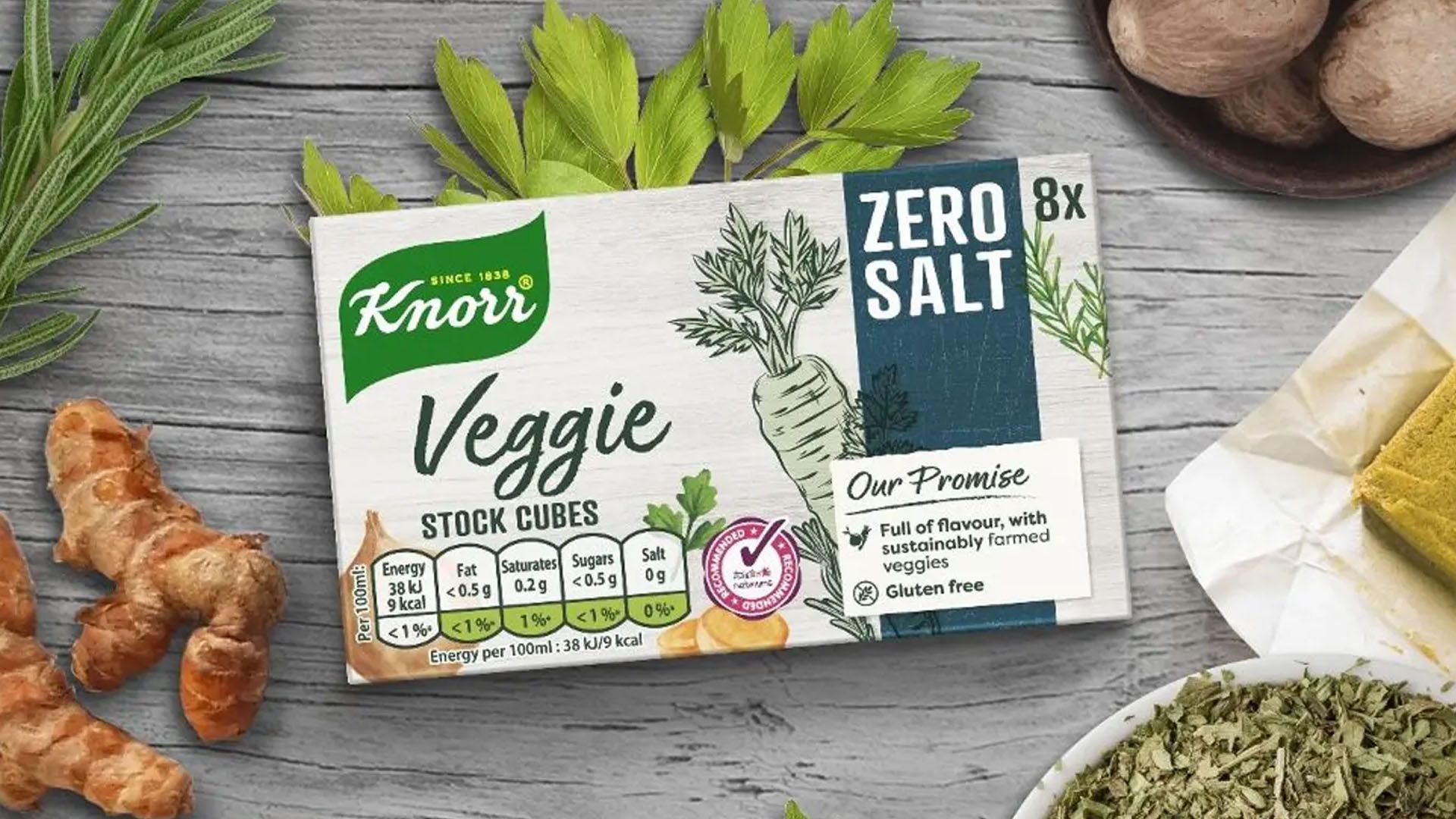 Packet of Knorr Veggie Zero Salt stock cubes on a table surrounded by herbs.