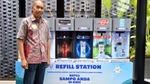 Man standing in front of Unilever’s in-store refill station in Indonesia. Machine has dispensers for products including TRESemmé, Clear and Lifebuoy.