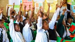 Children wearing their school uniforms eagerly holding up their hands to answer a question