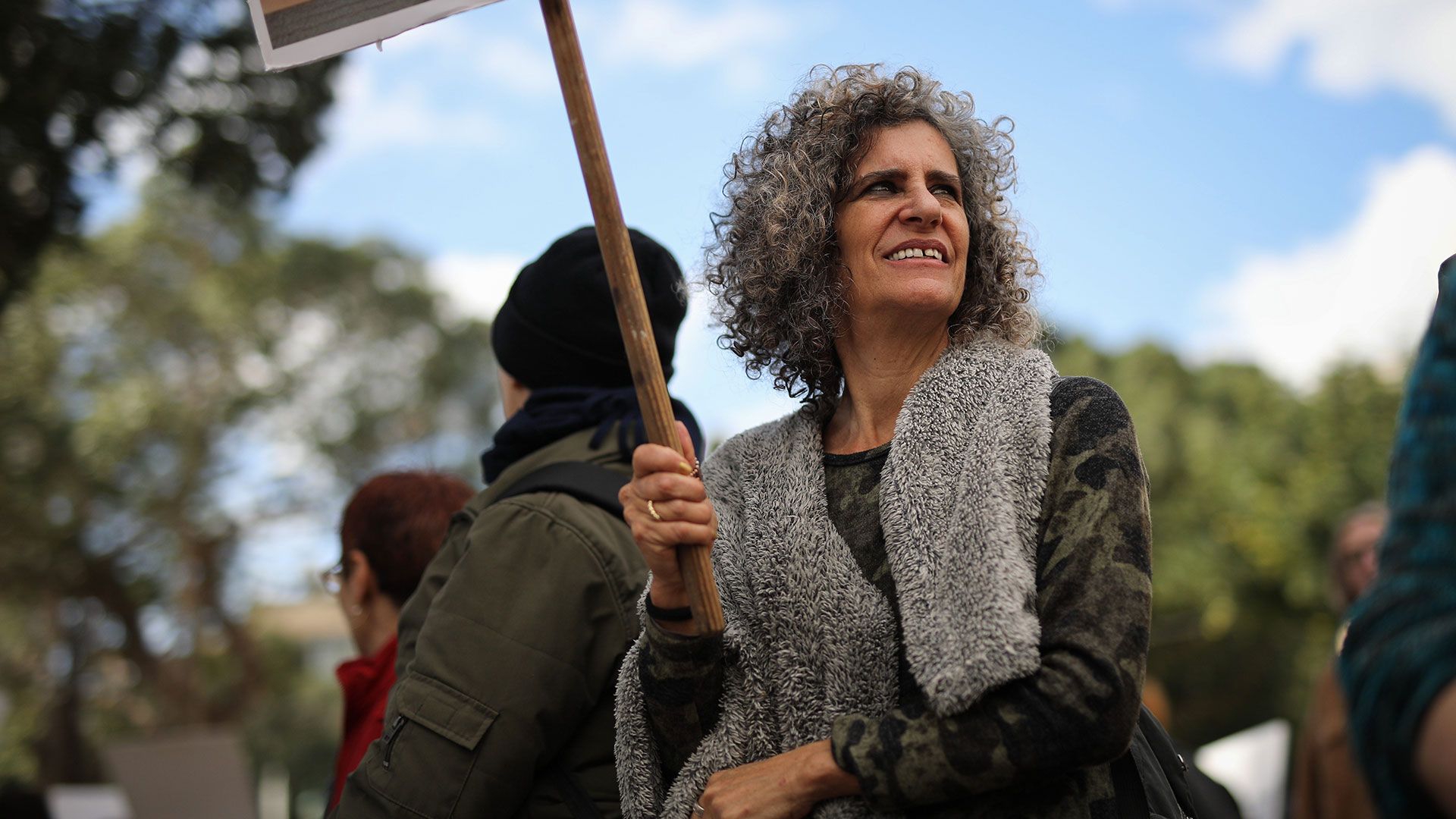 A woman holding a placard against a blue sky background