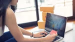 Young woman sitting in front of a laptop and using a credit card to pay for shopping online.