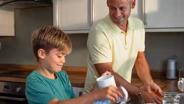 Father and young son in a kitchen doing the washing up together