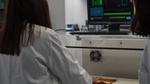 A Unilever scientist with long brown hair examines hair samples prepared by a robot at the Materials Innovation Factory