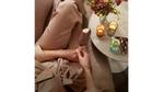 Woman sitting beside a table with a pack of Vegan Magnum Mini Almond ice creams with an unwrapped ice cream in her hand